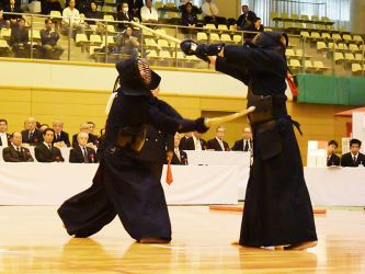 2回戦 宮戸伸之(和歌山)ド─ 坂田秀晴(山梨)
剣先を相手の竹刀に滑らせるように機を探る宮戸と、じっと動かさない坂田。宮戸が何度か打突を出す。相手の攻めには崩れない坂田だが、逆に攻めて打つ場面も少ない。延長に入り、ようやく坂田に大きな技が出るも、宮戸は見切っている。膠着状態になりそうな試合に決着をつけたのは宮戸の逆ドウ。それならとばかりに大きく踏み込んでメンを狙いつつ逆ドウを放つと、審判の旗がきれいに上がった。 それならとばかりに大きく踏み込んでメンを狙いつつ逆ドウを放つ
